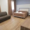 Camera d'albergo con letto matrimoniale, divano grigio e finestra con tende.
