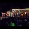 Persone che si esibiscono su un palco all'aperto di notte davanti a un pubblico.