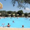 Ampia piscina all'aperto con ombrelloni e persone che nuotano e riposano.