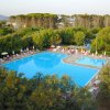 Piscina all'aperto circondata da lettini e alberi, vicino a una pineta, in un ambiente tranquillo.