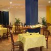 Una sala da pranzo con tavoli apparecchiati, tovaglie gialle e bottiglie su un bancone centrale.