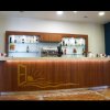 Bancone di un bar con bottiglie di alcolici esposte su mensole illuminate.