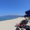 Spiaggia soleggiata con ombrelloni blu e persone rilassate su lettini.