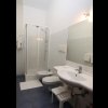 Un bagno moderno con box doccia, lavabo, bidet e specchio, pavimento in piastrelle blu.