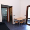 Stanza con tavolo per quattro, pavimento blu, accesso al bagno e porta finestra.