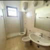 Bagno chiaro con doccia, WC, bidet, lavandino e specchio, finestra alta.
