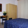 Camera con letto matrimoniale, copriletto blu, armadio in legno e scrivania con sedia.