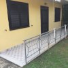 Terrazza di una casa gialla con rampa e tende bianche.