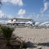 Una spiaggia con ombrelloni bianchi e un edificio sullo sfondo.