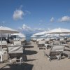 Spiaggia con lettini e ombrelloni bianchi.