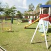 Parco giochi erboso con altalene e scivolo colorato.