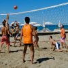 Partita di beach volley su sabbia con sei giocatori.