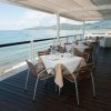 Tavoli apparecchiati su terrazza con vista mare.