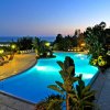 Piscina illuminata all'ora blu con vista sul mare.