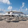 Spiaggia con lettini, ombrelloni e cabina bianca.