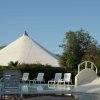 Piscina con sdraio bianche e tenda bianca sullo sfondo.