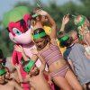 Bambini che ballano con una mascotte colorata.