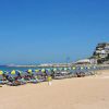 Spiaggia sabbiosa con lettini e ombrelloni gialli e blu.