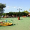 Parco giochi all'aperto con giostra, scivolo e bambini che giocano.