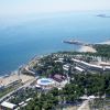 Vista aerea di un resort costiero con piscina, spiagge, edifici e mare azzurro.