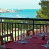 Tavoli apparecchiati su una terrazza con vista sul mare e vegetazione.