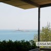 Vista sul mare con un faro in lontananza, vista da una terrazza coperta.