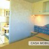 Interno di una casa mobile con letto matrimoniale e tavolo da pranzo. Decorazioni blu e verdi.