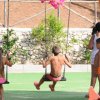 Bambini che giocano su altalene in un parco giochi all'aperto. Alcuni adulti li osservano.