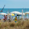 Spiaggia con ombrelloni bianchi e gente in riva al mare.