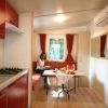 Cucina con mobili rossi, tavolo apparecchiato e persona seduta su una panca.