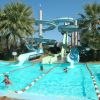 Piscina con scivoli d'acqua tortuosi e palme, bambini che nuotano.