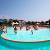 Grande piscina affollata, persone che si godono il sole e l'acqua.