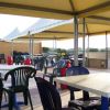 Terrazza coperta con tavoli e sedie di plastica, vista sui campi.