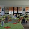 Sala da pranzo con tavoli apparecchiati con tovaglie verdi a motivi floreali.