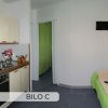 Cucina con divano verde e TV a parete.