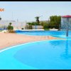 Piscina all'aperto con fontana a fungo rosso e aree pavimentate.