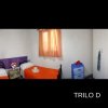 Stanza con due letti singoli, cuscini arancioni e finestra con tenda.