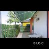 Patio esterno con tavolo rotondo, recinzione verde e tettoia.