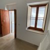 Stanza vuota con porta di legno aperta e finestra a doppio battente.