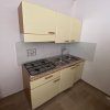 Una piccola cucina con mobili gialli, fornello a gas e lavello doppio.