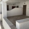 Un'ampia terrazza coperta con tre porte e pareti bianche.