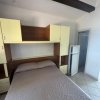 Letto matrimoniale sotto mensole, frigorifero vicino.