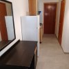 Corridoio con frigorifero, tavolo e specchio, porta in fondo.