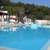 Una piscina all'aperto con lettini bianchi e alberi sullo sfondo.