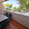 Balcone con tavolo e sedie, vista mare e pini.