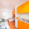 Cucina moderna arancione con tavolo apparecchiato, vista sul letto.
