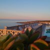 Vista sul mare con piscina e dettagli di una terrazza al tramonto.