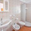 Bagno moderno con doccia, lavandino, bidet e rivestimento a mosaico.