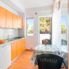 Una cucina luminosa con mobili arancioni, finestra aperta e tavolo apparecchiato con fiori.