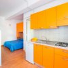 Interno di appartamento con cucina arancione e letti a castello blu.